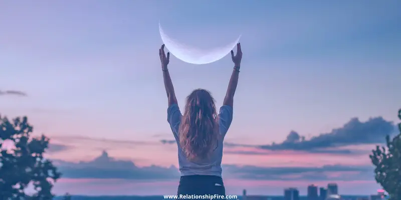 A woman looking like she's holding up the moon—Are Gemini Women Romantic